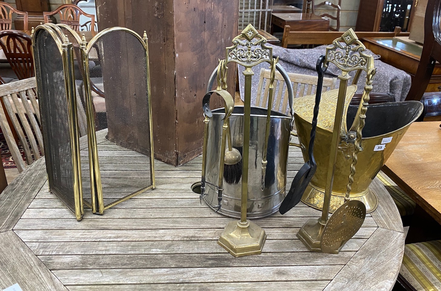 A Dutch embossed brass coal scuttle, a steel scuttle and sundry fire implements